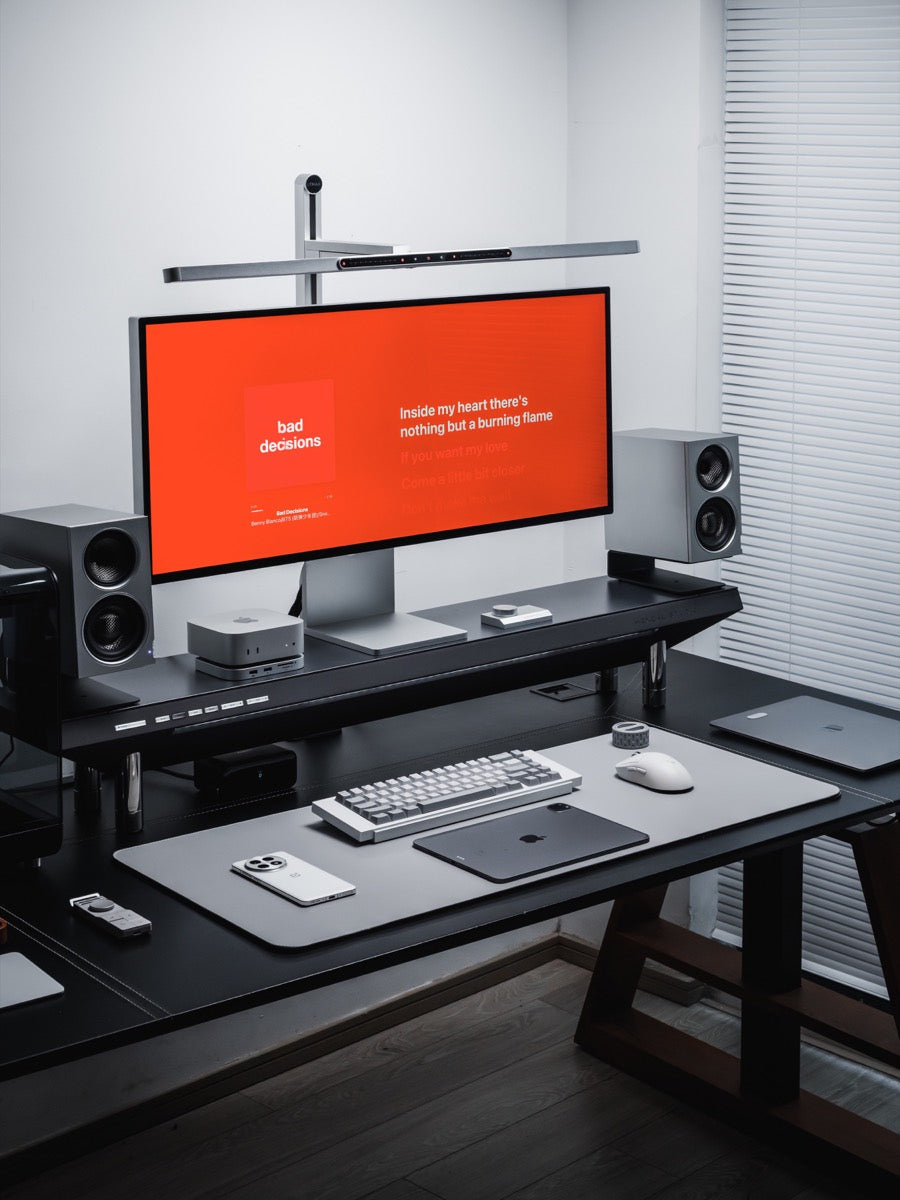 A pair of narrow SOVOX MiniMax3 Monitor speakers beside an ultrawide display on a clean desktop